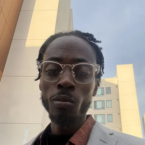 Dominique Taylor in clear-framed glasses and a gray suit